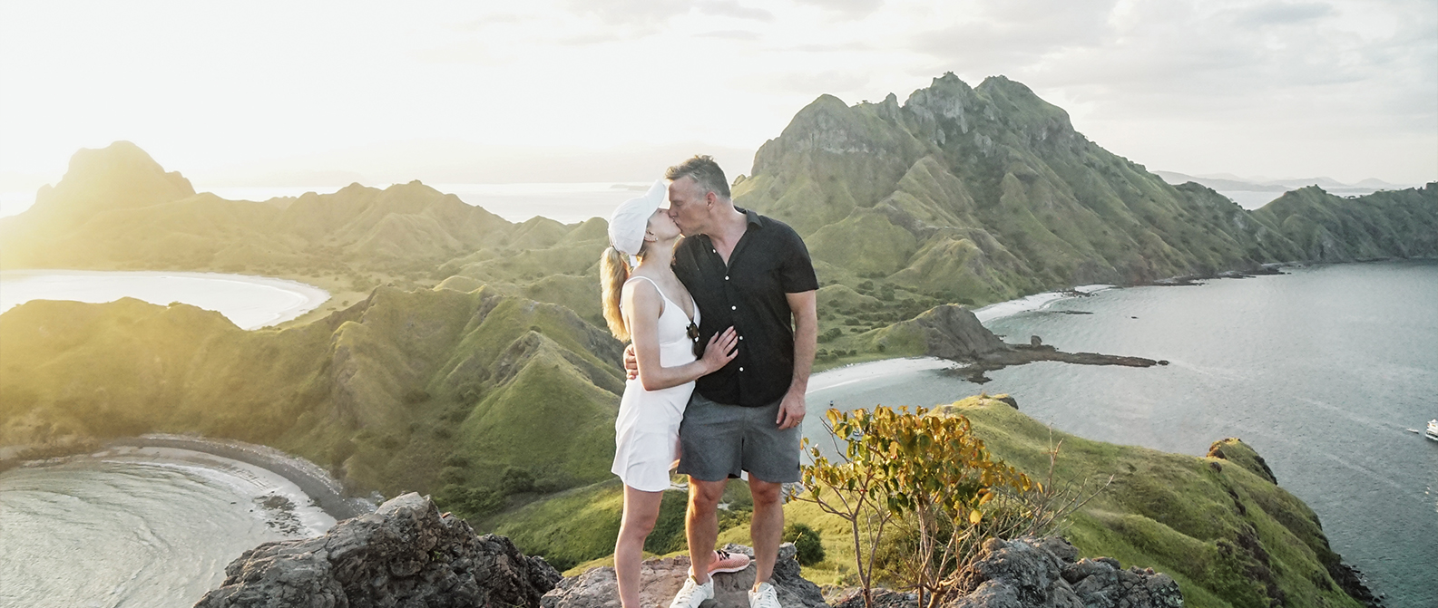 Tourist standing on Padar Island peak overlooking multiple bays
